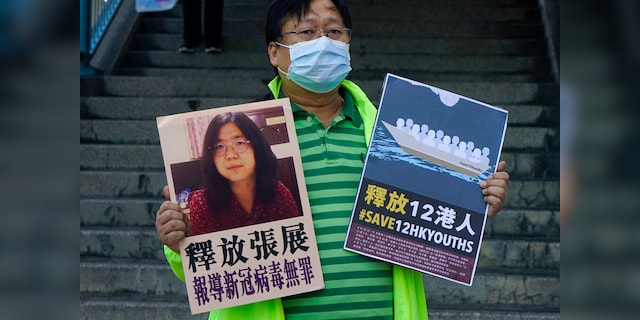 A pro-democracy activist holds placards with a photo of Chinese journalist Zhang Zhan outside the Chinese central government liaison office in Hong Kong.  (AP Photo / Kin Cheung)