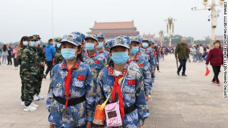 Pionierii chinezi care poartă măști de față participă la o ceremonie de ridicare a steagului în Piața Tiananmen pe 1 octombrie 2020 la Beijing, China.