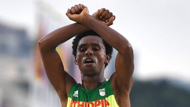 Feisa Lilisa, Etiopia, își încrucișează brațele deasupra capului la linia de sosire a cursului de atletism maraton masculin la Jocurile Olimpice Rio 2016 la Sampodromo din Rio de Janeiro pe 21 august 2016.
