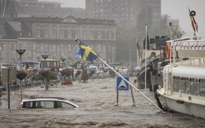 O mașină plutește în râul Meuse în mijlocul inundațiilor puternice din Lee & # xe8;  General Electric, Belgia, joi.