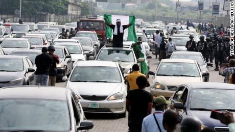 Un demonstrant ridică steagul nigerian în timpul unui protest pentru a marca prima aniversare a masacrului de la poarta Lekki Toll.
