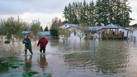 Surorile Miranda, stânga, și Christine Archer se plimbă prin apele de inundații din casa unchiului lor, luni, 15 noiembrie 2021, în Sedro Woolley, Washington.  (AP Foto/Elaine Thompson)