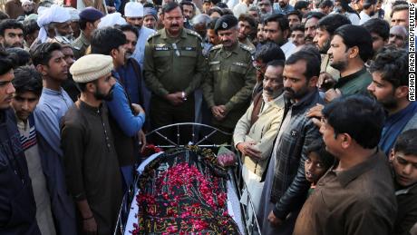 Oamenii stau lângă cadavrul unui bărbat care, potrivit poliției, a fost executat sumar de o mulțime, în satul Tulamba, centrul Pakistanului, pe 13 februarie 2022.