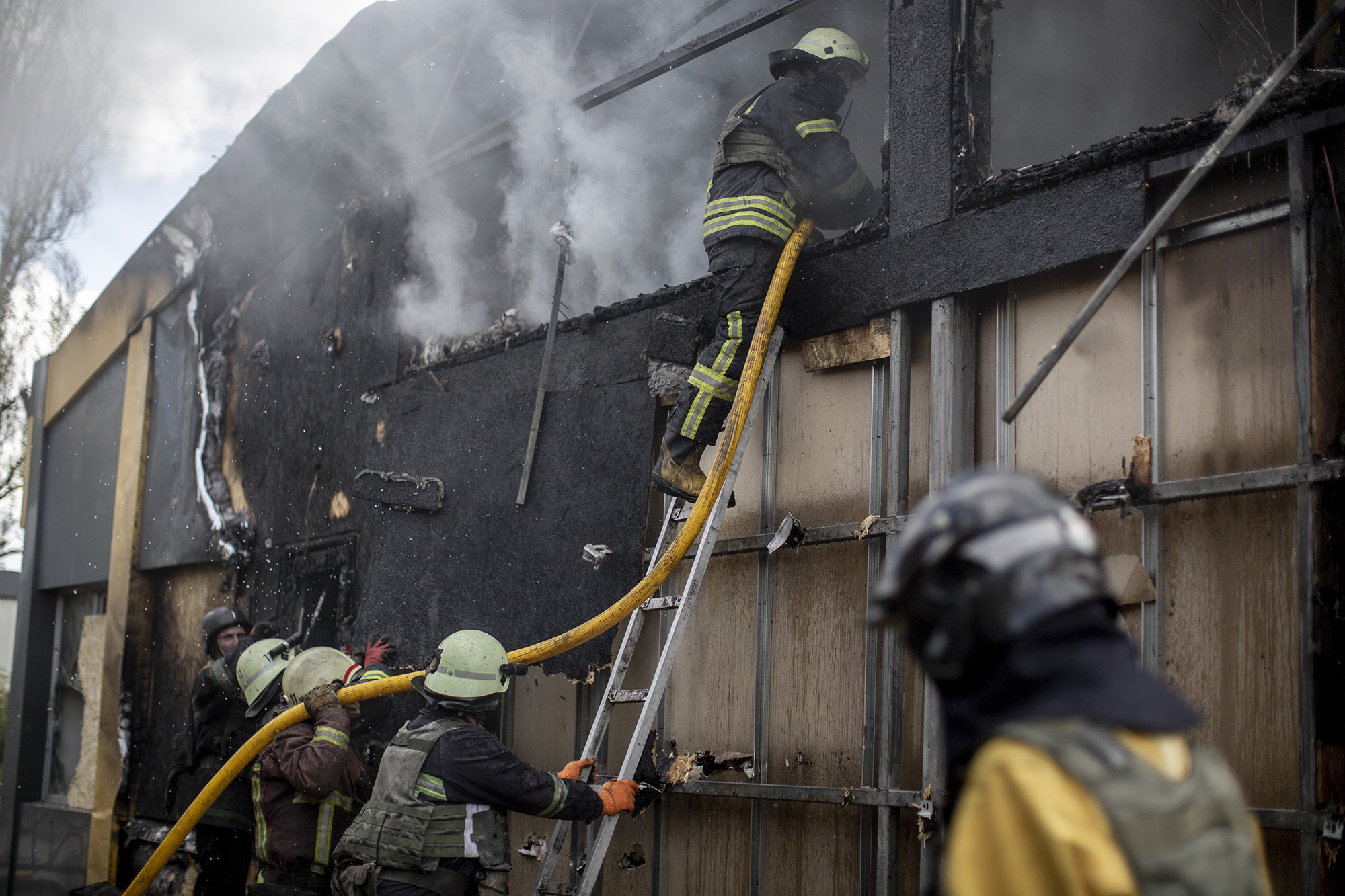 Pompierii lucrează la stingerea unui incendiu într-o zonă comercială după un atac cu rachetă în cartierul Saltivka din Harkov, Ucraina, pe 26 aprilie.