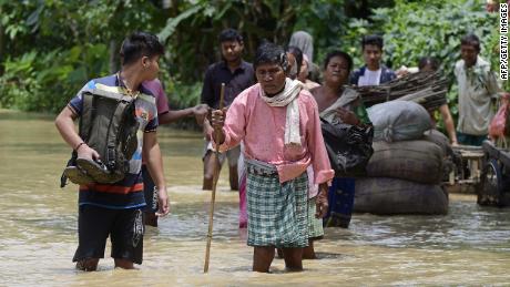 Oamenii merg în apele de inundații în districtul Nagoon din statul indian Assam pe 18 mai.