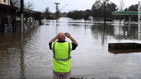 Un cetățean local face o fotografie a unui drum inundat din Camden, în sud-vestul Sydney, duminică, 3 iulie 2022.